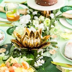 a table topped with lots of plates covered in gold leafy decorations and cake on top of them