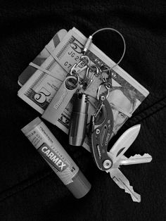 a pair of scissors sitting on top of money and keys next to some lighters