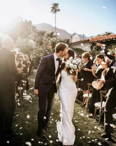 a bride and groom are walking down the aisle as confetti is thrown around them