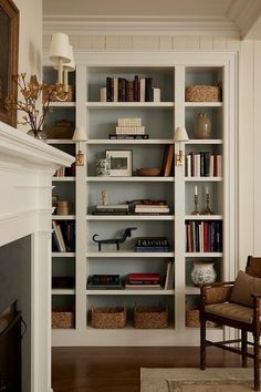 a living room filled with lots of books on top of white shelving units next to a fire place