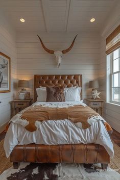 a large bed sitting in a bedroom next to two lamps and a cow head on the wall