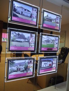 four televisions are hanging on the wall in front of a glass case with images of houses