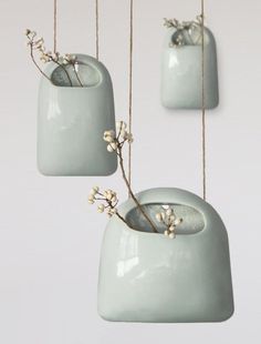 three ceramic vases hanging from strings with flowers in the bottom one is light blue