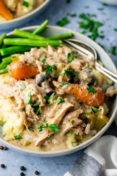 a bowl filled with chicken and vegetables on top of mashed potatoes, carrots and green beans