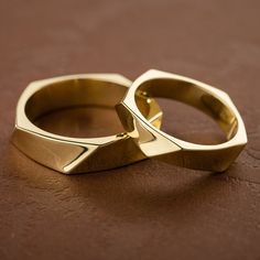 two gold wedding rings sitting on top of a brown leather surface with one ring in the middle