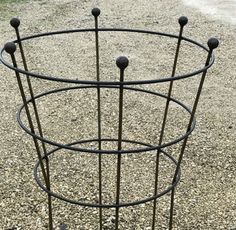 there is a metal stand with four balls in it on the gravel and dirt ground