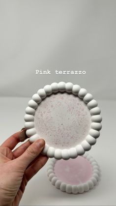 a hand holding a pink and white plate