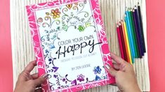 someone holding up a coloring book with colored pencils next to it and the words, color your own happy