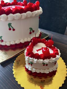 two cakes with cherries on them are sitting on the table next to each other