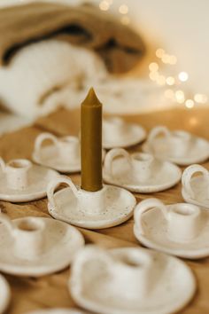 small white cups and saucers on a table with a tiny candle in the middle