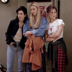 three women are standing in front of a building and pointing at something on the ground