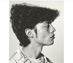 a black and white photo of a young man with curly hair on top of his head