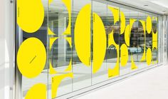 an image of a store front with yellow circles on the glass wall and white floor