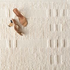 a pair of shoes sitting on top of a white rug next to a wooden shoe rack