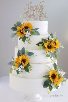 a three tiered cake with sunflowers and greenery on the top layer