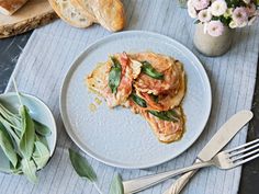 a white plate topped with food on top of a table next to bread and flowers