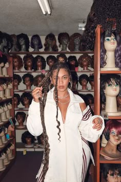 a woman is standing in front of many wigs