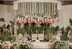 a wedding setup with chairs, flowers and greenery