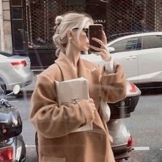 a woman is walking down the street while taking a selfie with her cell phone