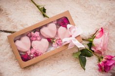 pink roses and heart shaped soaps in a cardboard box with ribbon on white fur