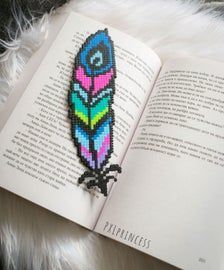 an open book with a colorful beaded feather on it