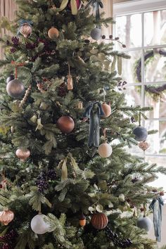 a christmas tree with ornaments hanging from it's branches and decorations on the top