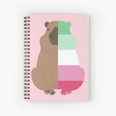 a brown bear sitting on top of a pink and green notebook