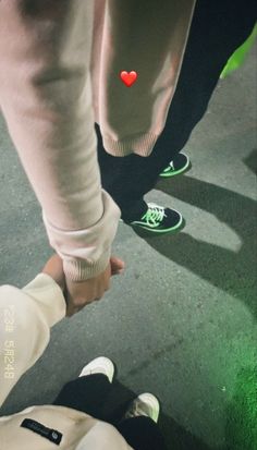 two people holding hands and walking down the street with their feet on each other's legs