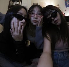 three young women sitting next to each other with their hands on their faces and wearing sunglasses