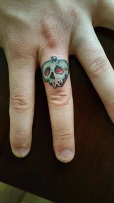 a person's hand with a skull tattoo on the middle of their ring finger