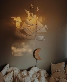 a bed with white sheets and a wooden sailboat hanging from the ceiling