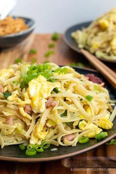 a plate full of noodles and vegetables with chopsticks next to it on a wooden table