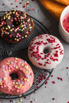 three donuts with sprinkles are on a plate