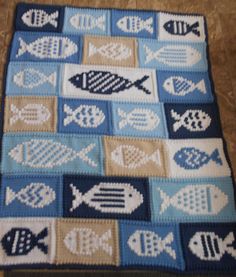 a crocheted rug with fish on it in blue and tan colors, sitting on the floor