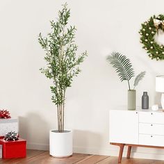 a living room decorated for christmas with wreaths on the wall and two plants in pots