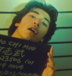 a man holding up a sign with writing on it in front of a jail cell