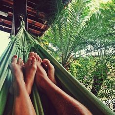 two people laying in a hammock with their feet up