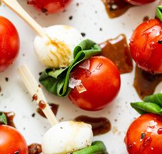 several tomatoes and mozzarella on skewers with sauce drizzled over them