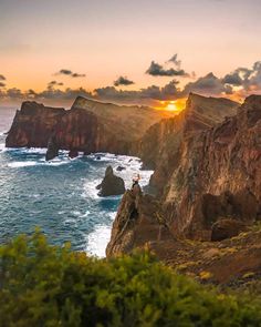 a person standing on the edge of a cliff overlooking the ocean at sunset or sunrise