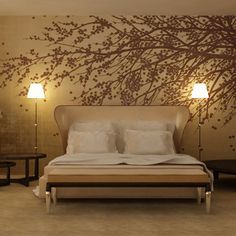 a bedroom with a tree painted on the wall next to a bed and nightstands