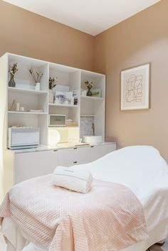 a white bed sitting in a bedroom next to a book shelf