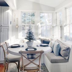 a dining room table with chairs and a bench in front of the window that is open