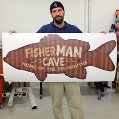 a man holding up a sign that says fisherman cave home of the big mouthe