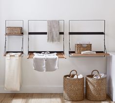 towels are hanging on the wall next to two baskets and towel racks in a white room