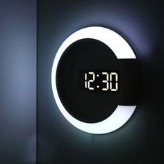 a clock that is on the side of a wall next to a mirror with it's time