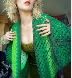 a woman with blonde hair wearing a green crocheted shawl over her shoulders