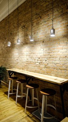 a long table with stools in front of a brick wall