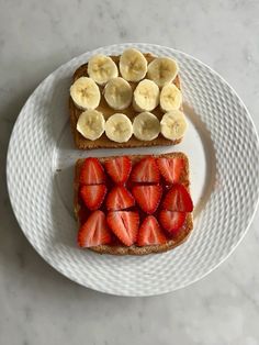 two slices of toast with sliced bananas and strawberries on top sitting on a plate