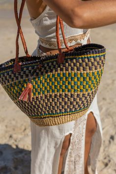 Our African Woven Basket is a versatile piece that adapts to your needs. This tote basket can be molded when wet and shaped to be round or narrow with a latch to close. With long leather handles, it's perfect for comfortable over-the-shoulder style.Measuring approximately 10-14 inches in width, 8-12 inches in height, and 6-8 inches in depth.Our exquisite African Artisan Baskets are a product of rich tradition, ethical sourcing, and sustainable craftsmanship. These unique baskets embody the spiri Beach Shoulder Bag With Handle Drop, Summer Vacation Straw Bag With Handle Drop, Basket Shoulder Bag With Detachable Handle For Shopping, Everyday Use Straw Tote Bag, Everyday Use Straw Tote Bag With Handle Drop, Daily Use Basket Bag With Detachable Handle, Daily Use Basket Shoulder Bag With Detachable Handle, Leather Basket Beach Bag For Everyday, Blue Beach Bag With Leather Handles For Travel