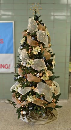 a small christmas tree with gold and silver decorations on it's base in a room